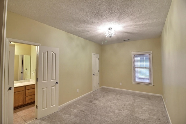 empty room featuring visible vents, light carpet, baseboards, and a textured ceiling