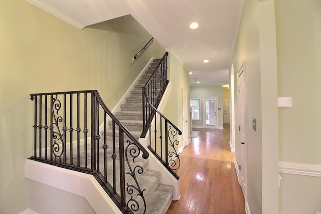 staircase featuring baseboards, ornamental molding, hardwood / wood-style flooring, and recessed lighting