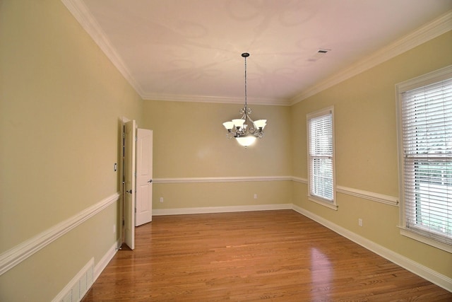 unfurnished room featuring baseboards, a notable chandelier, ornamental molding, and wood finished floors