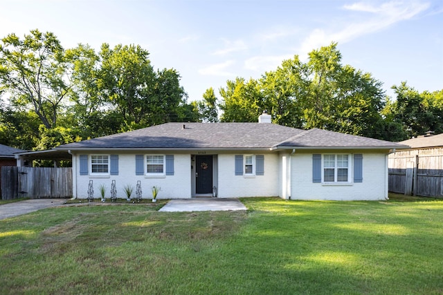 ranch-style home with an attached carport, brick siding, fence, a front lawn, and a chimney