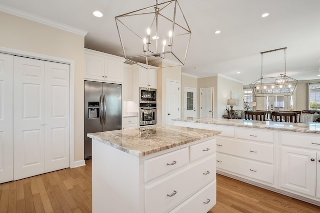 kitchen with appliances with stainless steel finishes, a chandelier, crown molding, and a kitchen island