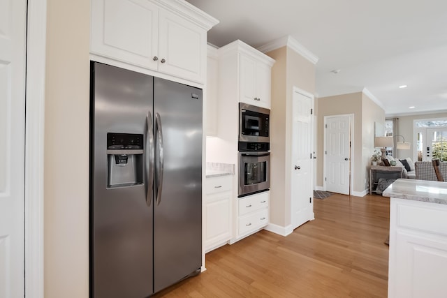 kitchen with stainless steel appliances, white cabinets, open floor plan, light stone countertops, and crown molding