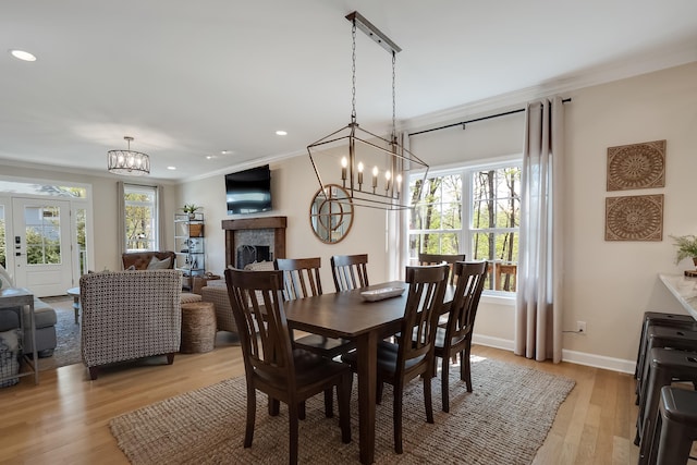 dining area with crown molding, a healthy amount of sunlight, a fireplace, and an inviting chandelier