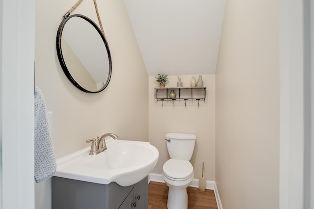 half bathroom featuring toilet, baseboards, wood finished floors, and vanity