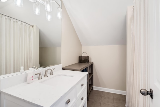 full bath with vanity, baseboards, vaulted ceiling, and tile patterned floors