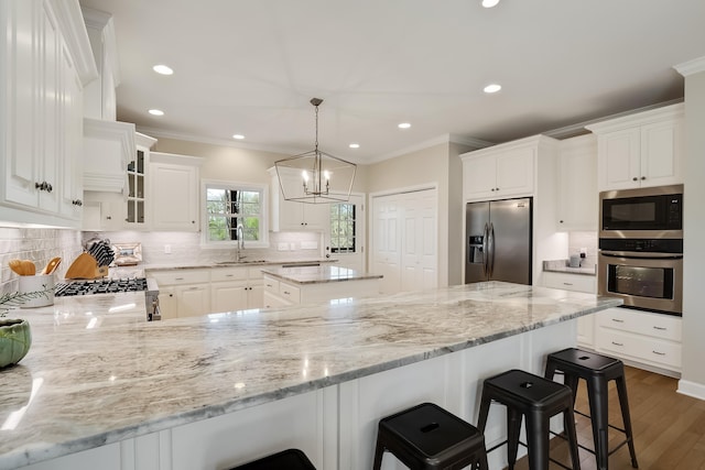 kitchen featuring stainless steel appliances, a peninsula, a sink, ornamental molding, and decorative backsplash