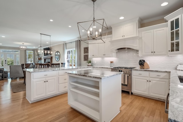 kitchen with high end stove, a center island, open shelves, an inviting chandelier, and crown molding