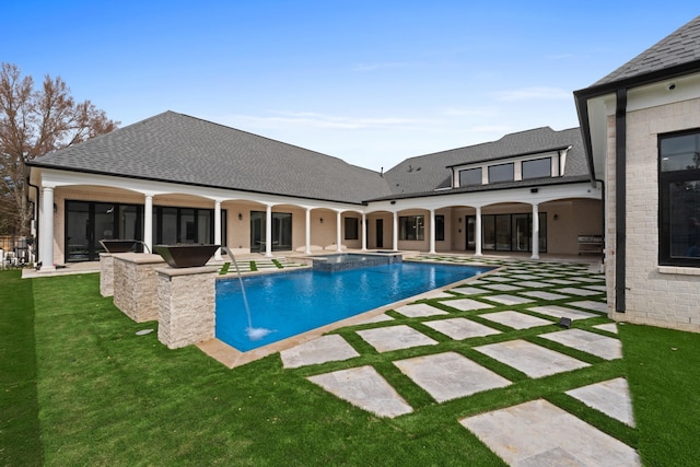 view of pool featuring a pool with connected hot tub, a patio area, and a lawn