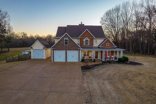 traditional-style house with a chimney, a porch, metal roof, driveway, and a front lawn