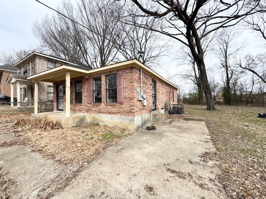 view of property exterior with brick siding, a porch, and central air condition unit