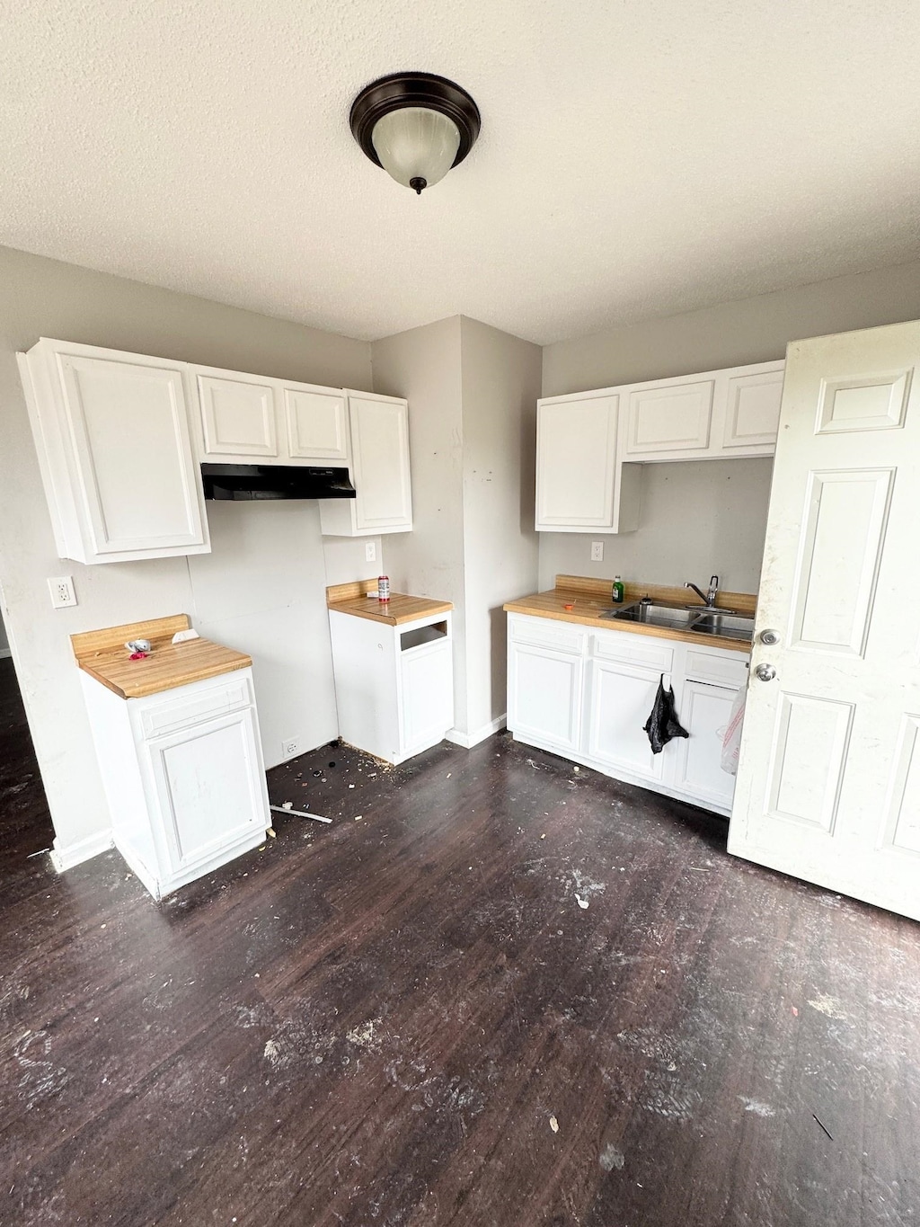 kitchen featuring baseboards, white cabinetry, dark wood-style flooring, and a sink