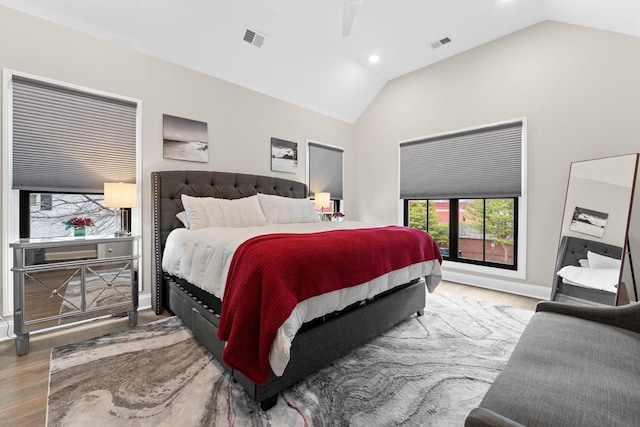 bedroom with high vaulted ceiling, baseboards, visible vents, and wood finished floors