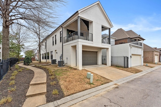 view of front of property featuring brick siding, fence, a balcony, cooling unit, and driveway