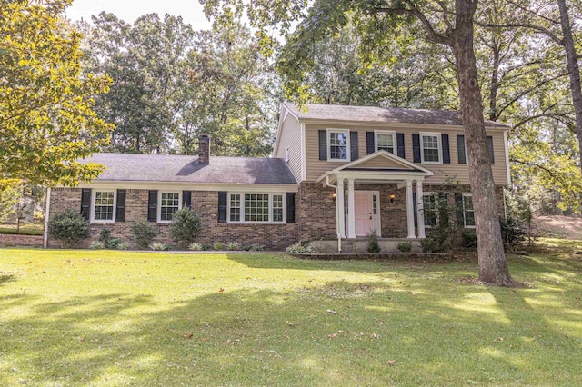 view of front facade featuring brick siding, a front lawn, and a chimney