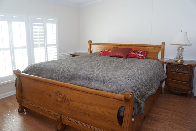 bedroom featuring ornamental molding, baseboards, and wood finished floors