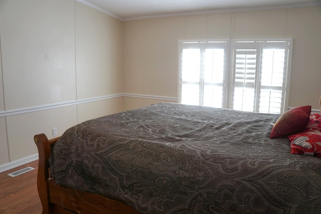 bedroom with visible vents, crown molding, and wood finished floors