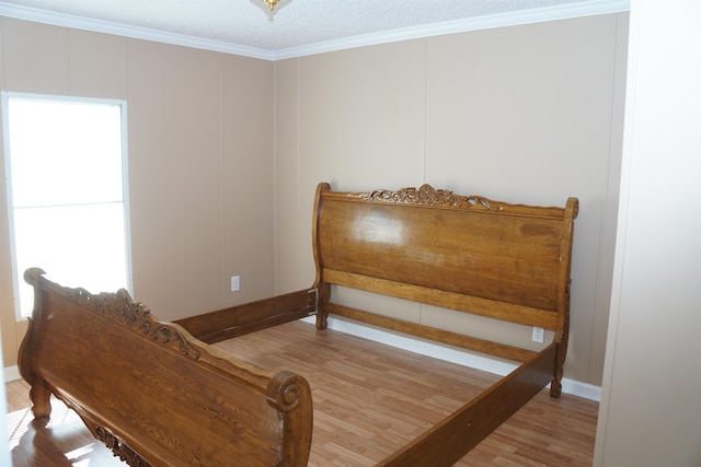 bedroom featuring baseboards, wood finished floors, and crown molding