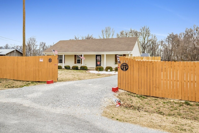 view of front facade with a porch, driveway, and fence