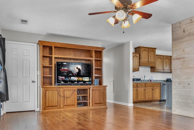 unfurnished living room with baseboards, visible vents, ceiling fan, light wood-type flooring, and a sink