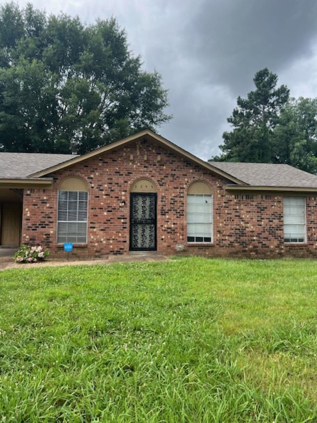 single story home with a front yard, brick siding, and roof with shingles