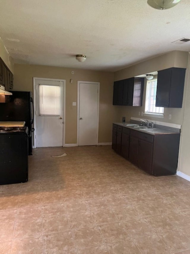 kitchen featuring range hood, a sink, a textured ceiling, range, and baseboards