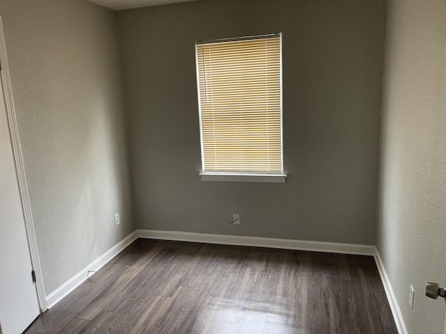 unfurnished room with dark wood finished floors and baseboards