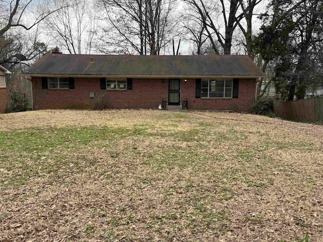 single story home with brick siding, a front lawn, a chimney, and fence