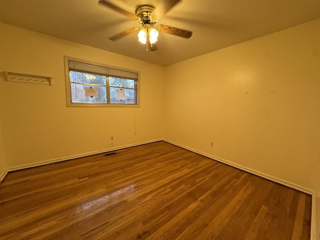 empty room featuring visible vents, dark wood finished floors, and a ceiling fan