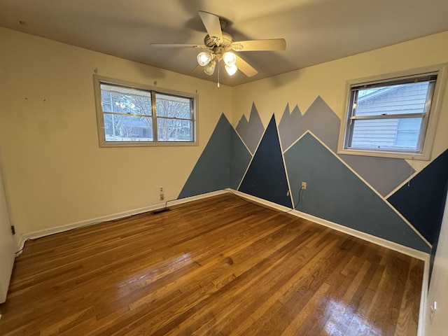 unfurnished room with visible vents, ceiling fan, baseboards, and wood finished floors