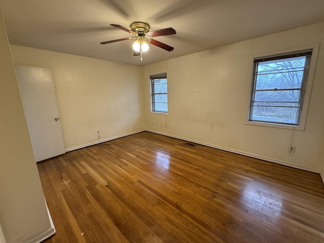 empty room with a ceiling fan, visible vents, and wood finished floors