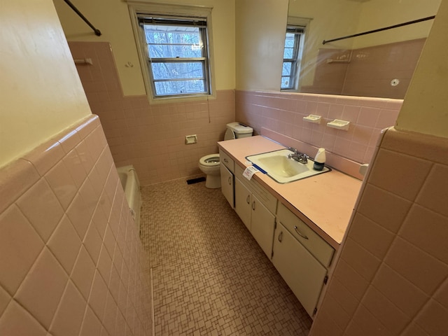 bathroom featuring toilet, a wainscoted wall, tile walls, vanity, and tile patterned floors