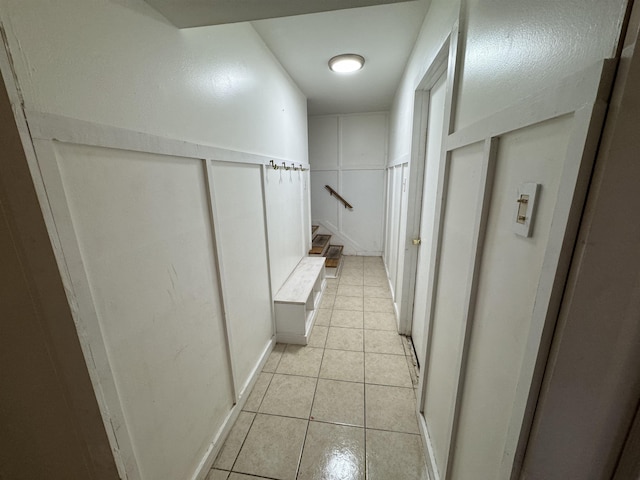 hall featuring light tile patterned floors and stairs