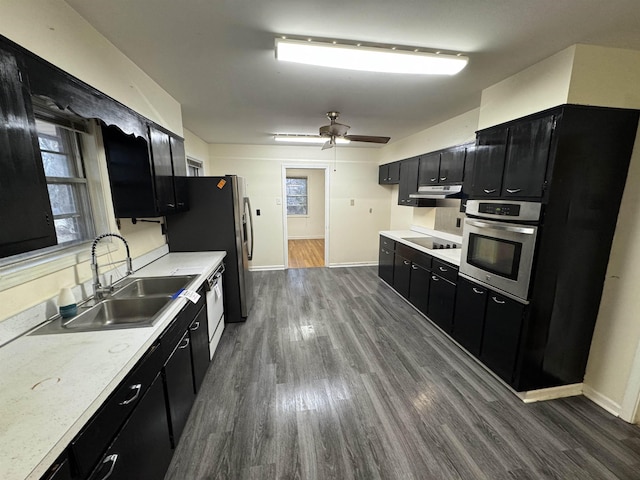 kitchen with black electric stovetop, dark cabinetry, a sink, and oven