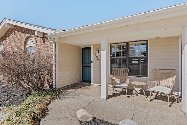 doorway to property featuring a patio and brick siding