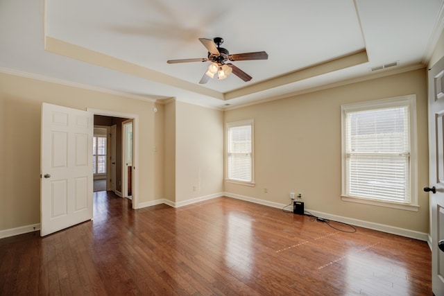 spare room with a tray ceiling, hardwood / wood-style flooring, plenty of natural light, and visible vents