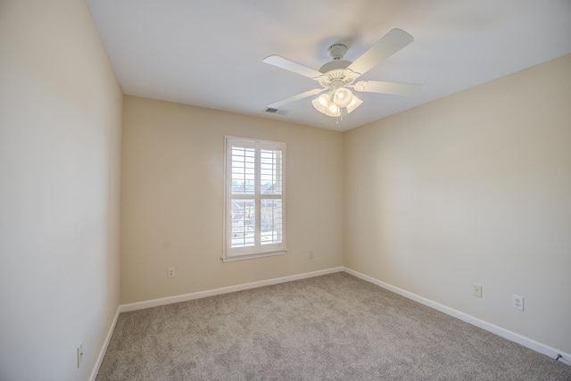 spare room with carpet floors, visible vents, ceiling fan, and baseboards