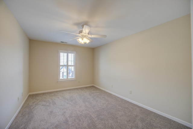 carpeted empty room featuring baseboards, visible vents, and a ceiling fan