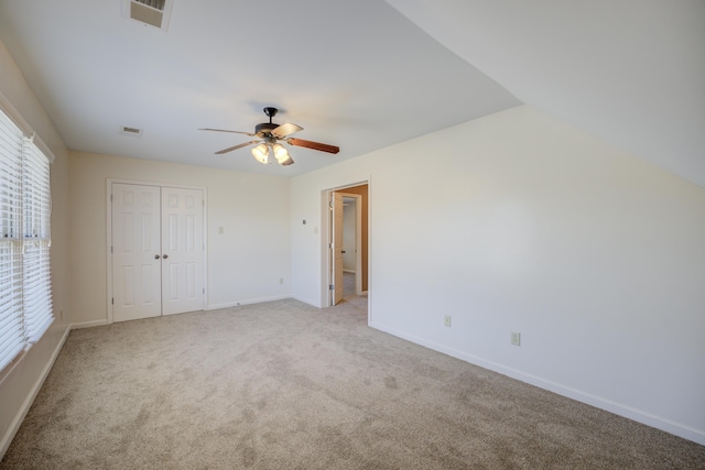 unfurnished bedroom featuring a closet, light colored carpet, visible vents, ceiling fan, and baseboards