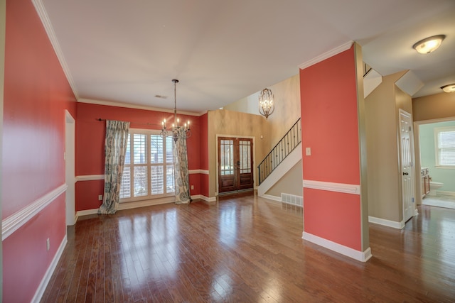 unfurnished dining area featuring hardwood / wood-style flooring, a notable chandelier, baseboards, stairs, and crown molding