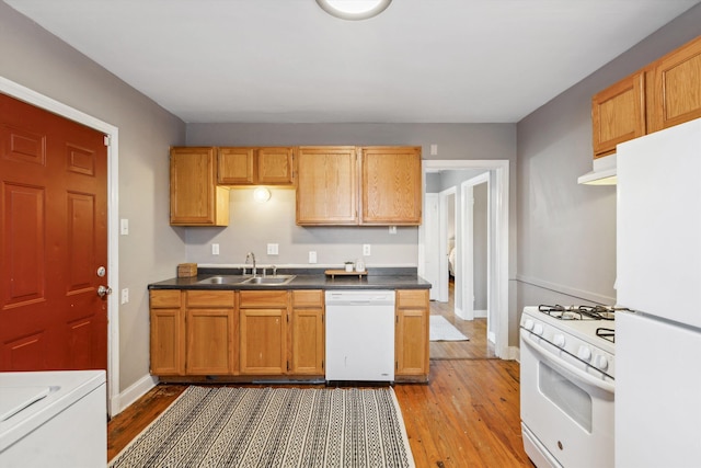 kitchen with under cabinet range hood, light wood finished floors, a sink, and white appliances