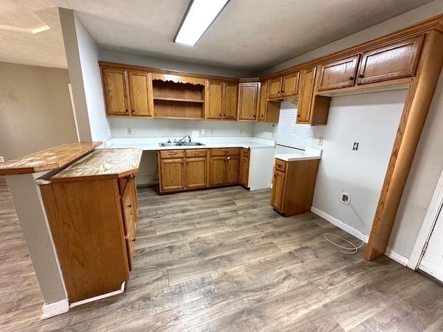 kitchen featuring open shelves, light wood-style floors, brown cabinetry, and a sink