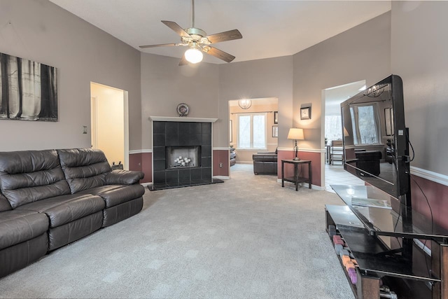 living room featuring carpet floors, a high ceiling, a tiled fireplace, and baseboards