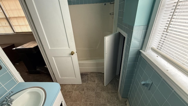 full bathroom with a sink, a shower, a washtub, and tile walls