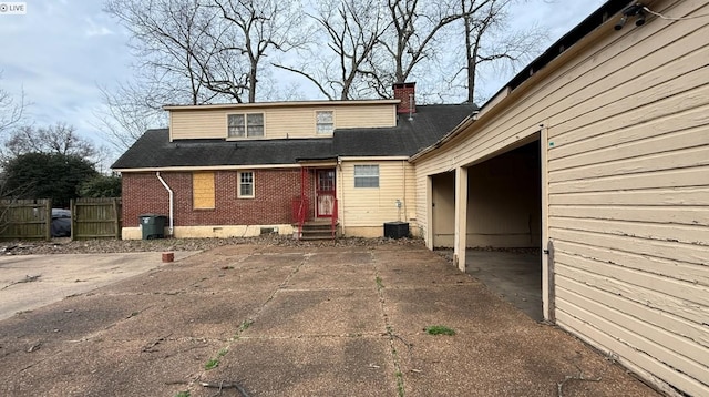 rear view of house featuring central AC, brick siding, fence, crawl space, and a chimney