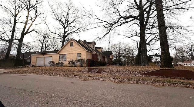 view of property exterior featuring an attached garage and driveway