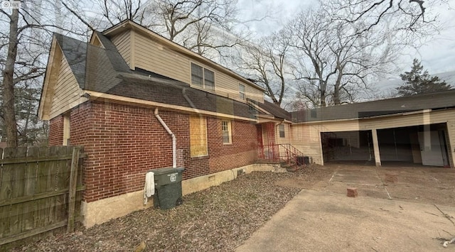 view of side of home with a garage, concrete driveway, crawl space, fence, and brick siding