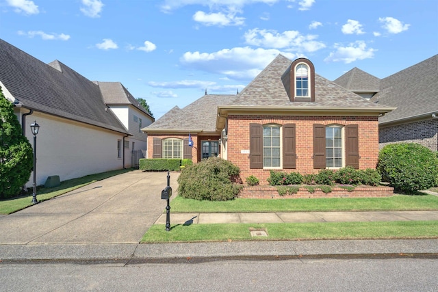 view of front of house with brick siding and roof with shingles