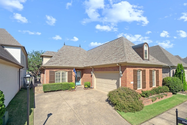 view of front of property with an attached garage, a shingled roof, concrete driveway, and brick siding