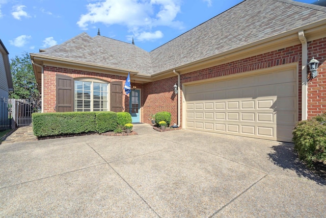 view of front facade featuring an attached garage, brick siding, fence, concrete driveway, and roof with shingles