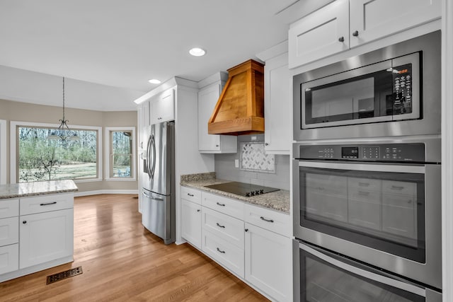 kitchen with stainless steel appliances, visible vents, white cabinetry, custom exhaust hood, and light wood finished floors